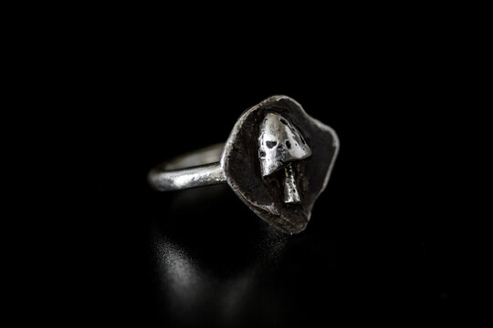 Silver ring with a mushroom design on a dark background. The ring features a unique leaf shape, highlighting the intricate details of the mushroom.