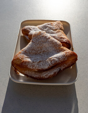 Due sfogliatella calde artigianali ricoperte di zucchero a velo servite su un vassoio di carta ecologica, colazione tradizionale italiana illuminata dalla luce naturale del sole
