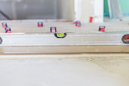 Spirit level checking flooring surface during home renovation
