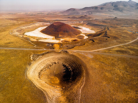 Aerial view of Lake Meke, two volcanic craters and a ash cone, crossed by a road in between, near Karapinar, Konya, Turkey. Distant mountains can been seen on the horizon
