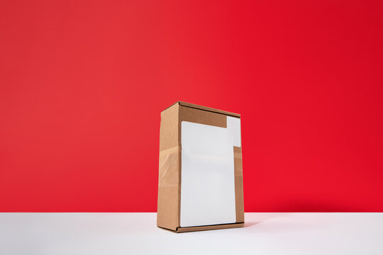 Cardboard Box Package with Blank White Label Mockup on Red Background