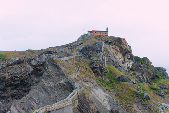 San juan de gaztelugatxe hermitage standing on a rocky island cliff, connecting to the basque country coastline by a winding stone staircase over the cantabrian sea
