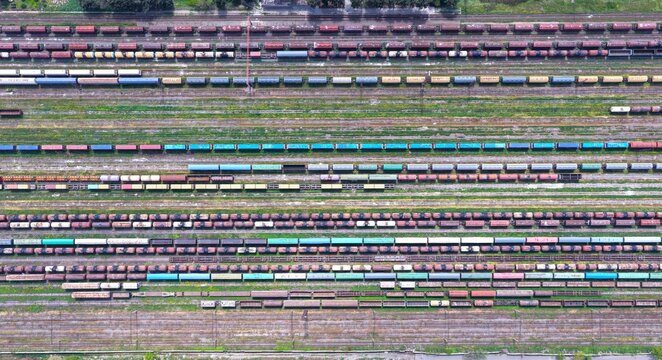 Aerial view of a large railway yard with numerous parallel tracks filled with colorful freight train cars and cargo containers in Tbilisi, Tbilisi, Georgia.