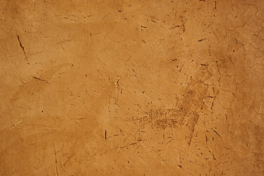 Brown adobe mud wall texture with embedded straw background