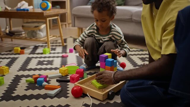 African American father and boy building tower using wooden toy blocks on floor. Clip suitable for parenting campaigns, early childhood education, and family wellness advertisements