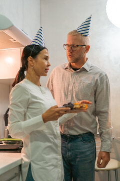 Couple Birthday Kitchen Celebration: Mature man woman share cake; intimate birthday celebration in kitchen setting.