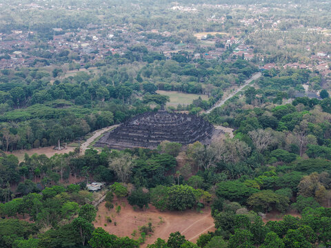 Aerial view of Borobudur Temple surrounded by lush green trees and vegetation in Magelang, Jawa Tengah, Indonesia.