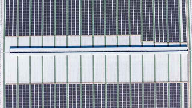 Aerial view of a large industrial building roof covered with extensive solar panel arrays in Salatiga, Central Java, Indonesia.