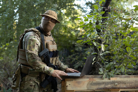 A soldier works on a laptop in the field while carrying out a mission.