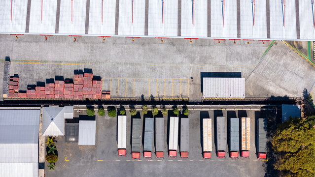 Aerial view of a logistics warehouse facility with rows of parked semi-trucks and cargo containers in the loading yard in Salatiga, Central Java, Indonesia.