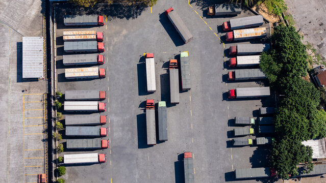 Aerial view of a busy logistics depot with numerous semi-trucks parked in organized rows on an asphalt lot in Salatiga, Central Java, Indonesia.