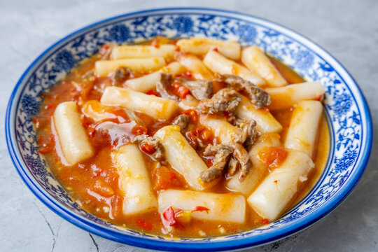 A plate of stir-fried rice cakes with beef and tomato