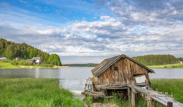 Abandoned wooden dock house by calm lake under cloudy sky