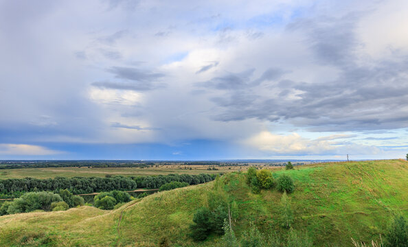 Lush meadow slopes rise toward hazy forest line