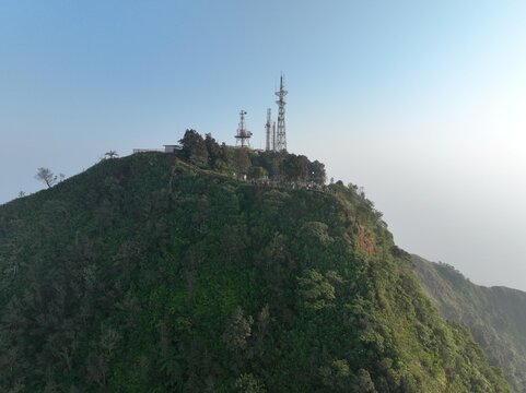Aerial view of Triangle Sky Telomoyo on Mount Telomoyo, featuring communication towers atop a lush, forested mountain peak in Kecamatan Ngablak, Jawa Tengah, Indonesia.