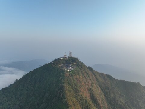 Aerial view of Triangle Sky Telomoyo situated on the peak of Mount Telomoyo surrounded by lush green slopes and a sea of clouds in Kecamatan Ngablak, Jawa Tengah, Indonesia.