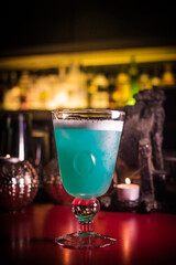 Blue cocktail served in a glass at a bar during evening hours with dim lighting © Phototora