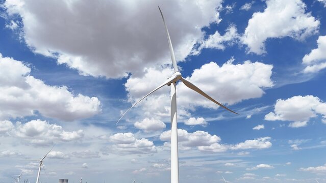 white wind turbine generator under blue sky and white clouds