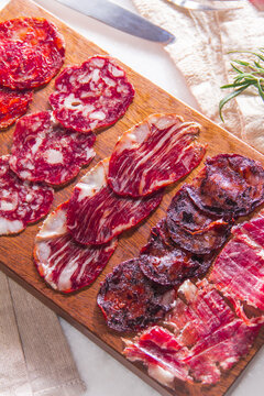 Variety of cured meats arranged on a wooden board during a food gathering