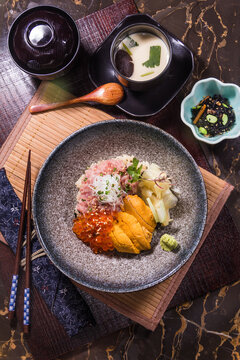 Sushi dish served with soup and side items on wooden table in restaurant setting