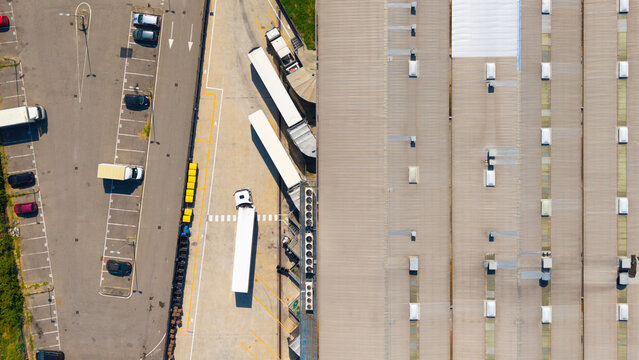 Aerial view of Esselunga Spa logistics facility with trucks parked at loading bays and a large warehouse roof Sesto Ulteriano, Lombardia, Italy.