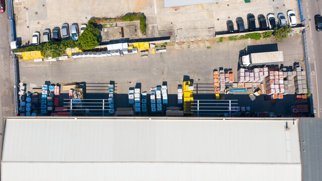 Aerial view of a distribution center and warehouse for thermal and acoustic insulation materials with stacked construction supplies and parked vehicles in San Giuliano Milanese, Lombardy, Italy.