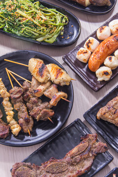 Diverse assortment of grilled skewers and side dishes on plates at a gathering