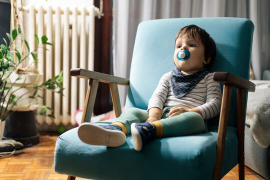 Toddler boy relaxing in armchair with pacifier
