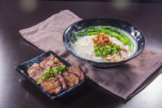 Delicious bowl of noodle soup served with grilled meat and fresh herbs