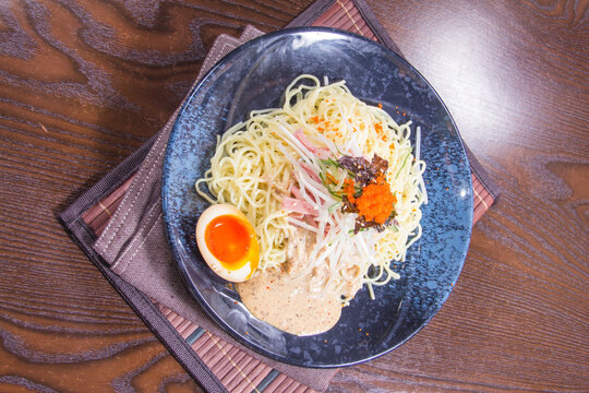 Noodles served on a dark plate with garnishes and an egg at a local restaurant