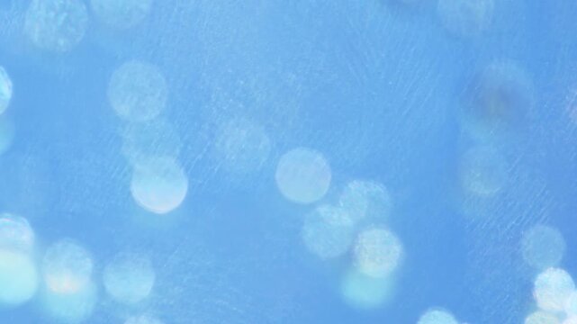 Abstract sparkling bokeh blue background with shimmering light refractions and sun flares from carbonated water with gas bubbles, glowing caustics and effervescent texture.