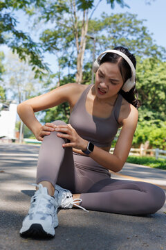Woman experiencing knee pain during outdoor workout, stopping her run due to a sports injury, symbolizing physical discomfort and health issues