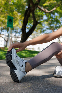 Woman stretching her leg muscles during a warm-up exercise outdoors, preparing for a workout, demonstrating flexibility and dedication to a healthy fitness lifestyle
