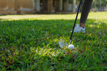 Person preparing to hit golf ball with iron club on green grass fairway, engaging in sport and leisure activity outdoors, focusing on precision and technique © MINAE