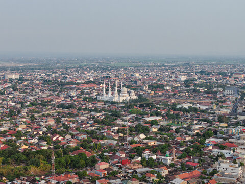 Aerial view of the Sheikh Zayed Grand Mosque surrounded by dense urban rooftops and greenery in Surakarta, Jawa Tengah, Indonesia.