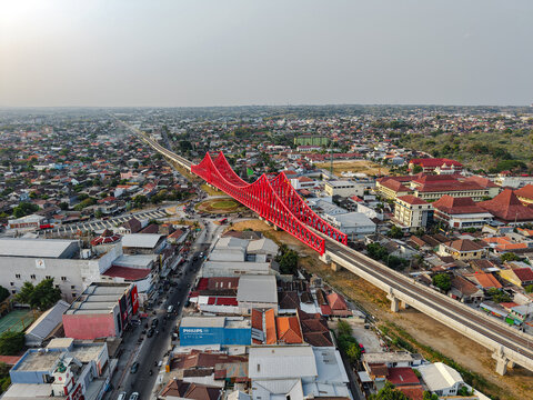 Aerial view of Jembatan Kereta Api Joglo, a prominent red steel railway bridge spanning over the urban landscape of Surakarta, Jawa Tengah, Indonesia.