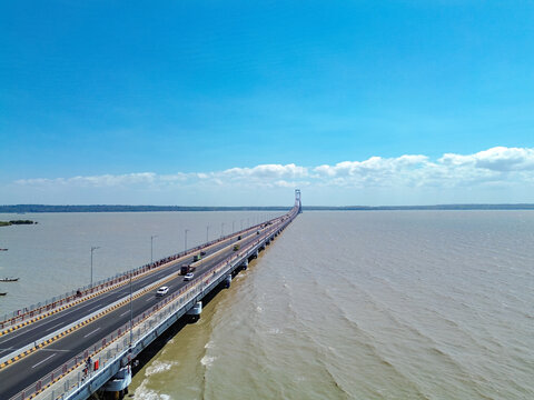 Aerial view of Suramadu Bridge spanning the Madura Strait with cars driving on the asphalt road under a clear blue sky Surabaya, East Java, Indonesia.
