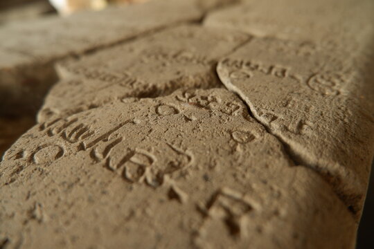 Ancient Javanese script engraved on historical stone inscription tablet in museum close up