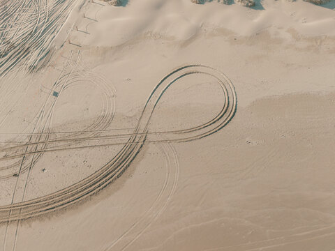 Aerial view of Birubi Point sand dunes featuring intricate tire tracks forming an infinity symbol pattern in the soft sand at Anna Bay, New South Wales, Australia.