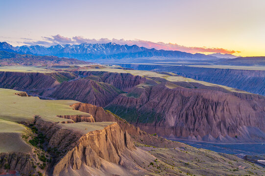 Majestic Anjihai Grand Canyon featuring steep cliffs and distant snowy mountains at sunset in Xinjiang, China