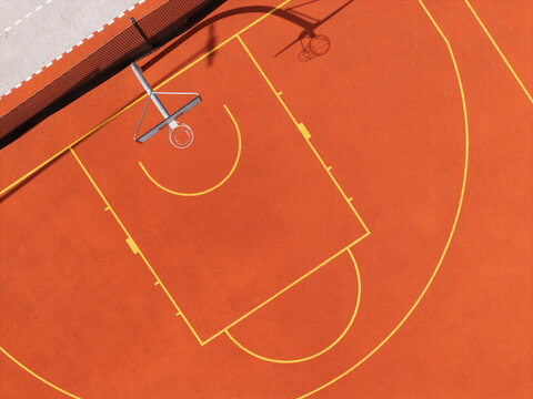Aerial view of a vibrant orange basketball court with yellow court markings and a hoop in Gdansk, Poland.