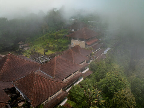 Aerial view of the abandoned P.I. Bedugul hotel surrounded by dense tropical forest and thick mist in Kecamatan Baturiti, Bali, Indonesia.