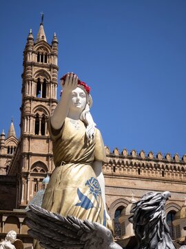 Artistic low-angle perspective of Santa Rosalia's ceremonial vessel float with its silver eagle prow framed by the ancient arches and towers of Palermo Cathedral.
