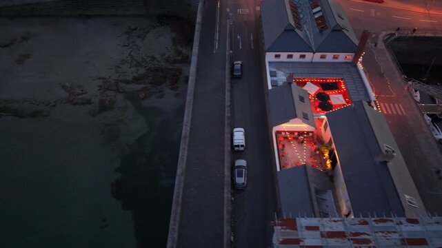 St Peter Port Harbour,Guernsey,Channel Islands.Low dropping footage at dusk over the Slaughterhouse pub lit up at the side of Albert Marina ending over the beach of Havelet Bay