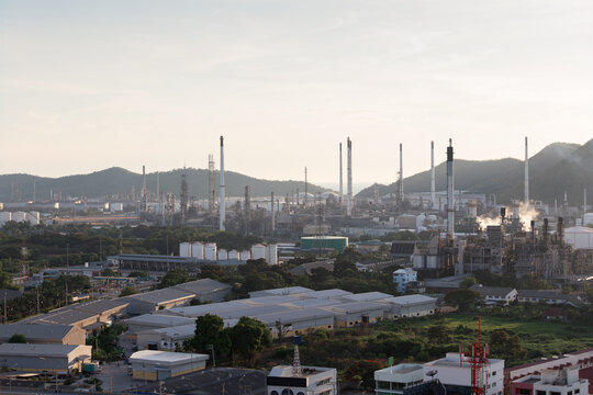 Aerial view oil refinery plant Laem Chabang industrial estate featuring tall smokestacks, storage tanks, factory buildings, mountain landscape, heavy energy production fuel manufacturing power sector.
