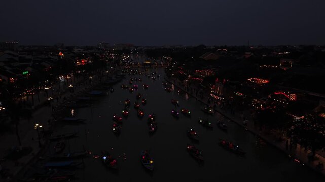 Boats adorned with colorful lanterns float on the river in Hoi An, Vietnam, as the city transforms into a vibrant scene at night