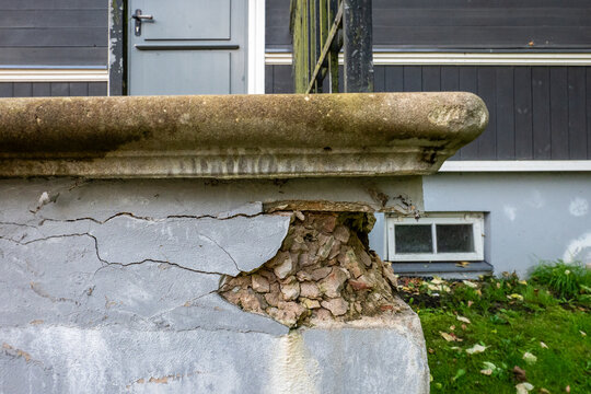 Crumbling Concrete Wall Exposes Stone Aggregate Beneath Cracked Plaster