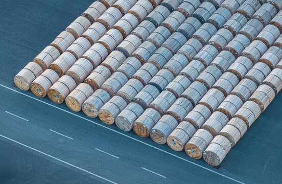 Aerial view of hundreds of large wooden industrial reels arranged in organized rows at an outdoor storage yard in Livorno, Tuscany, Italy.