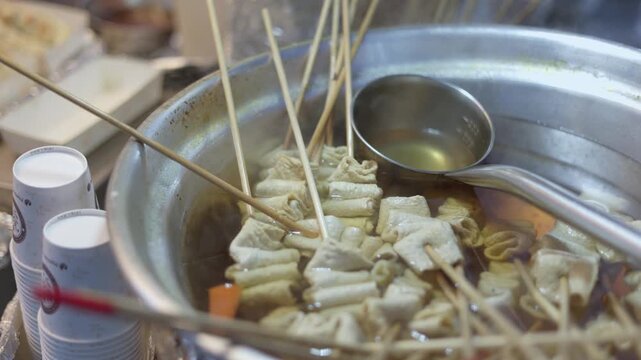 Korean Fish Cake Skewers (eomuk or odeng) Served In Warm Broth From A Metal Pot At A Street Food Stall. High-angle Shot