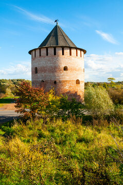 Veliky Novgorod Russia, historic architecture background. A round brick tower called Alexeevskaya or White tower with a conical roof on a green hill among autumn trees